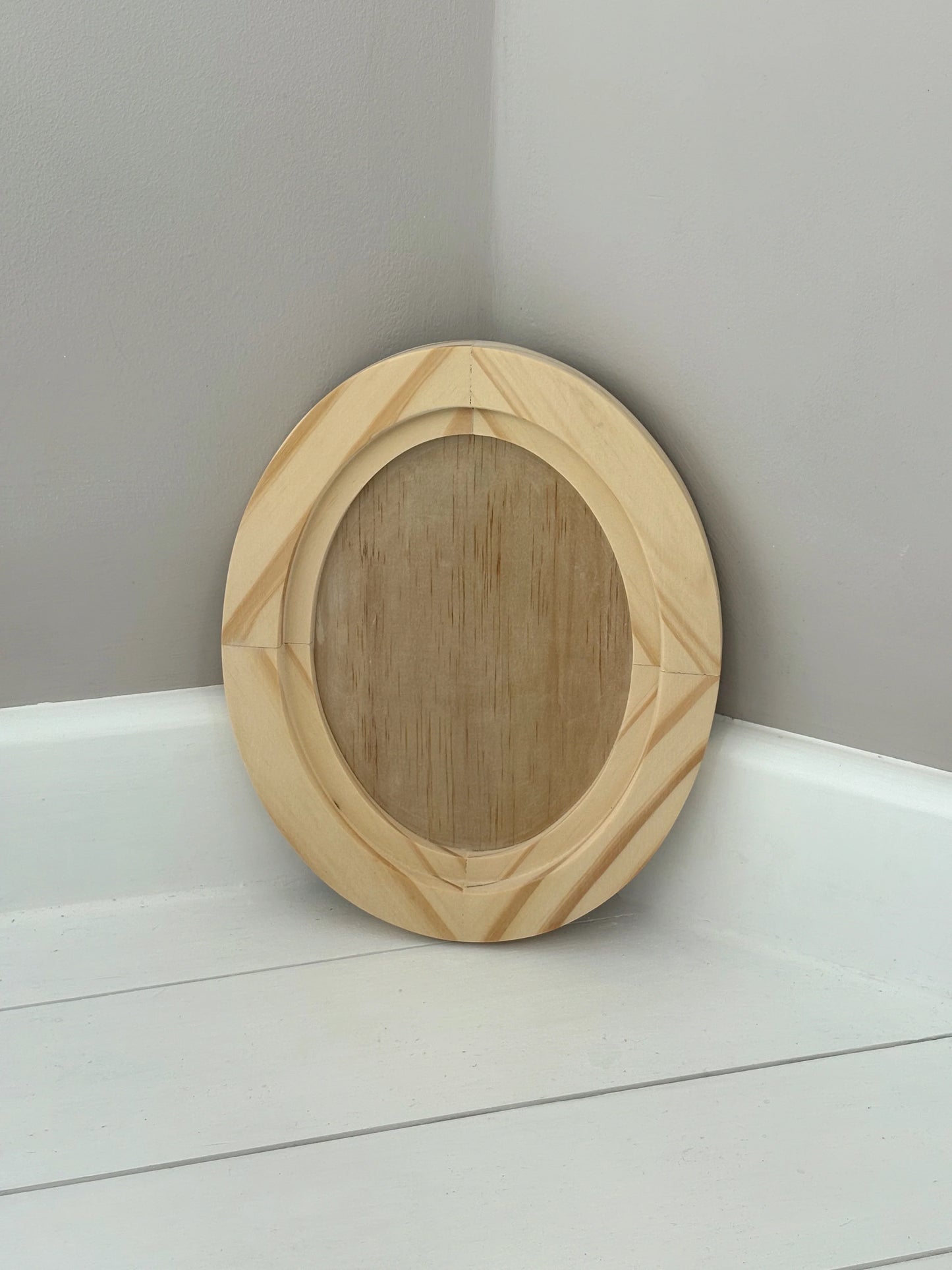 Wooden circular object on a white surface with a gray background