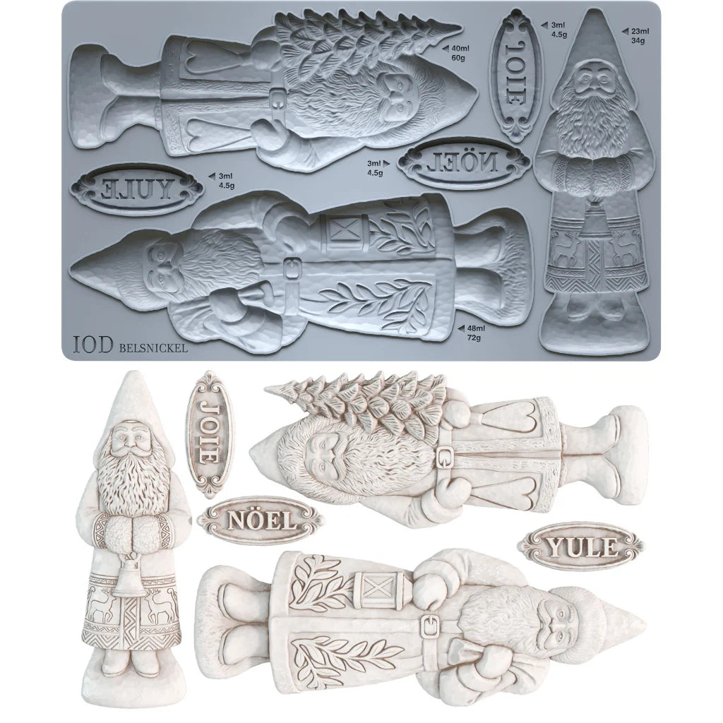 A mold-making product display showing a gray rectangular mold tray with Christmas-themed cavities and several light off-white sculpted figurines and labels above it, including a gnome, a fish, a tree, and words such as JOE, NOÉL, and YULE.