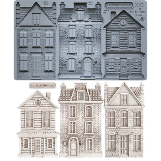 A set of miniature Victorian-style house molds and cutouts, including a gray metal mold tray at the top and three finished light beige house cutouts below on a white background.