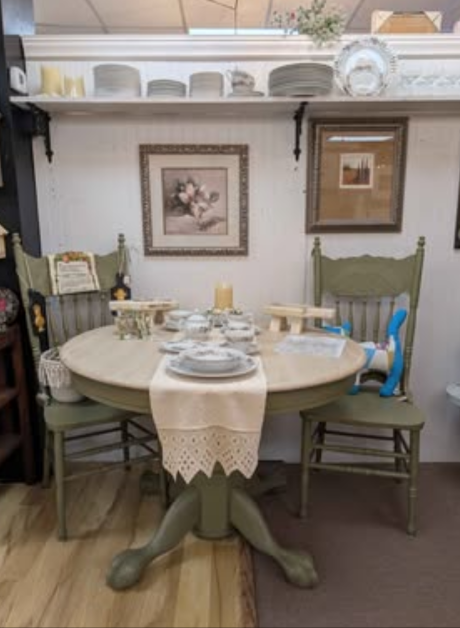 Dining room with round table and chairs, decorated with a lace tablecloth and candles.
