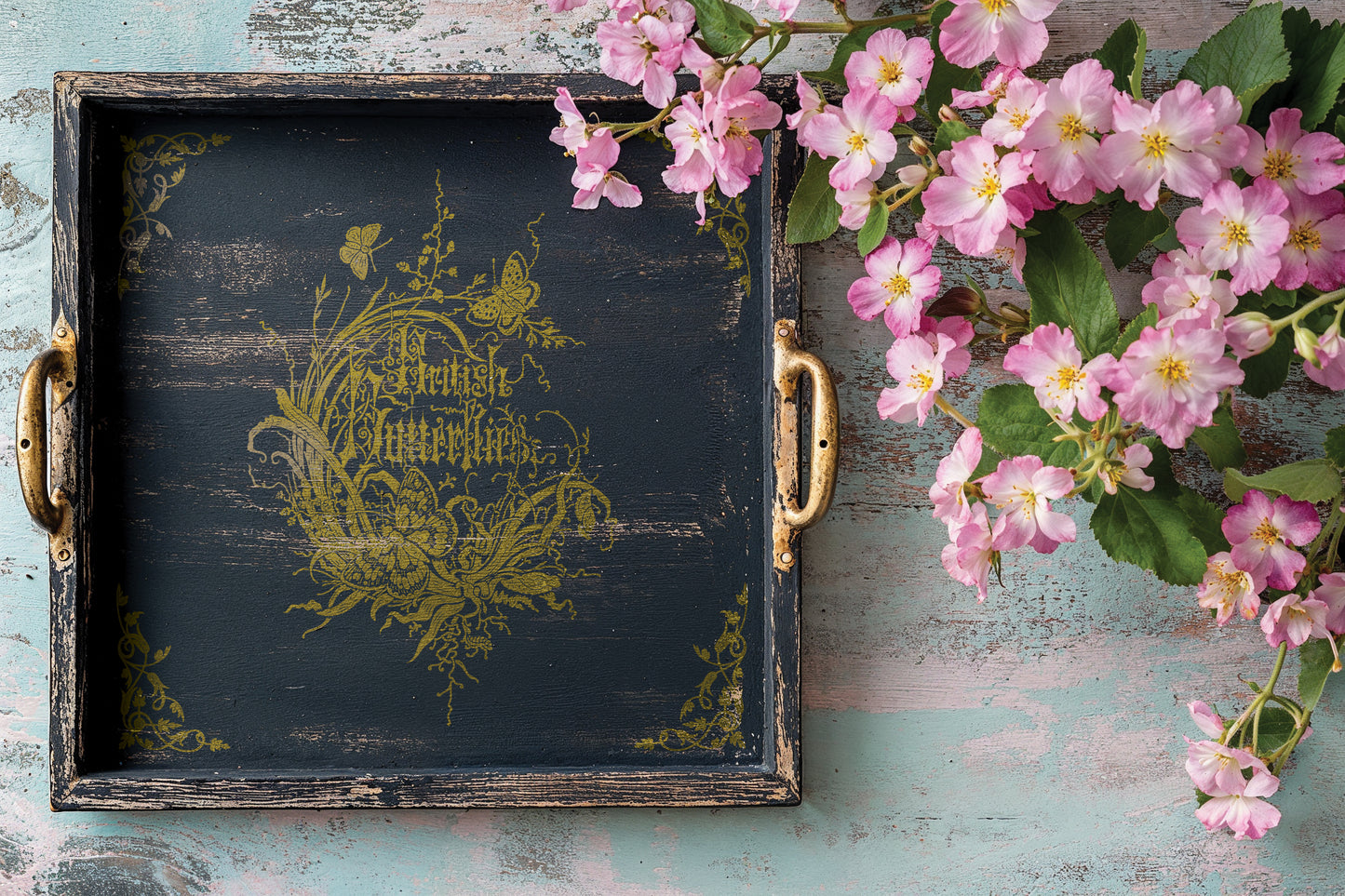 Decorative tray with floral design and pink flowers on a rustic wooden surface
