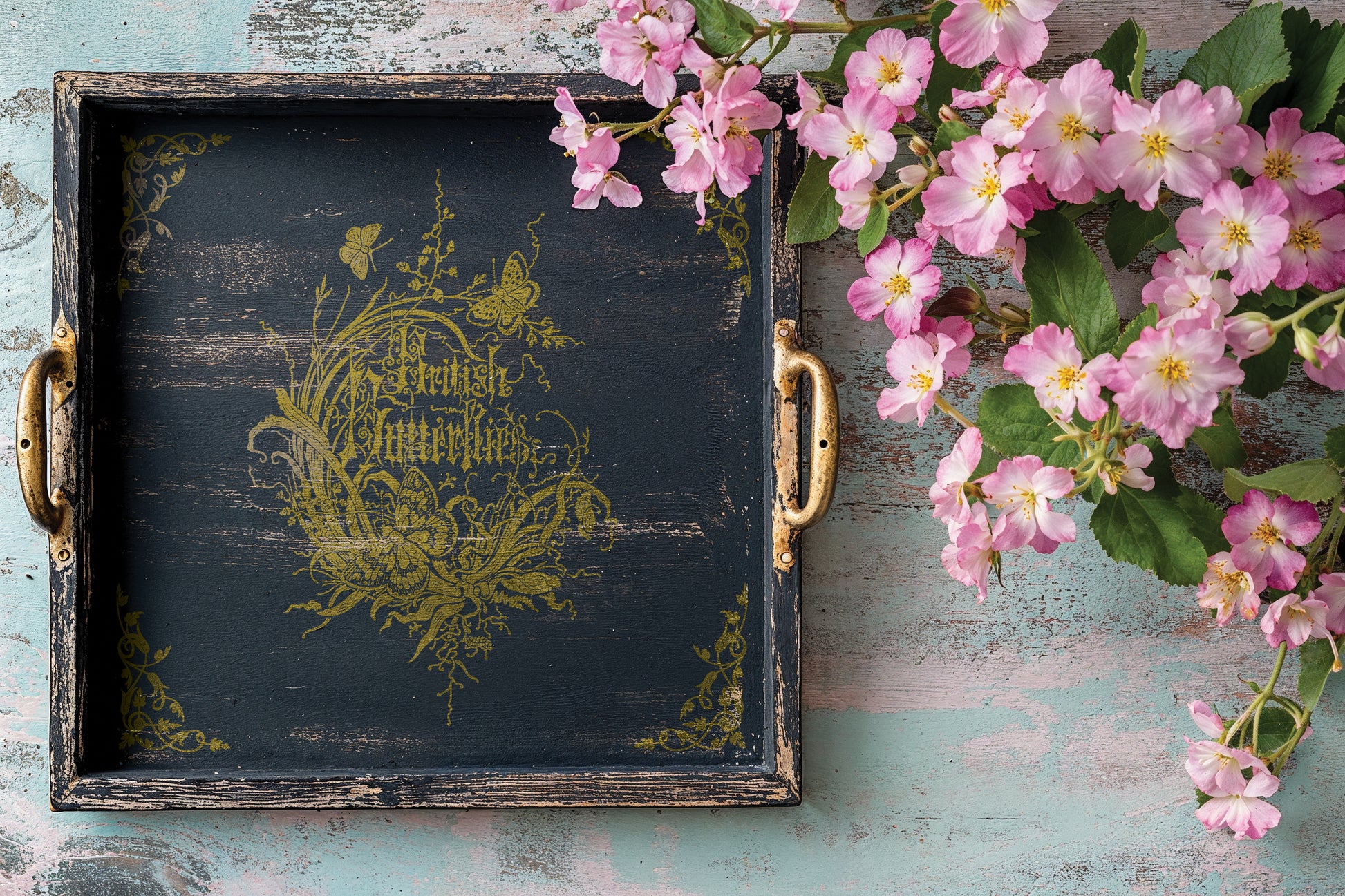 Decorative tray with floral design and pink flowers on a rustic wooden surface