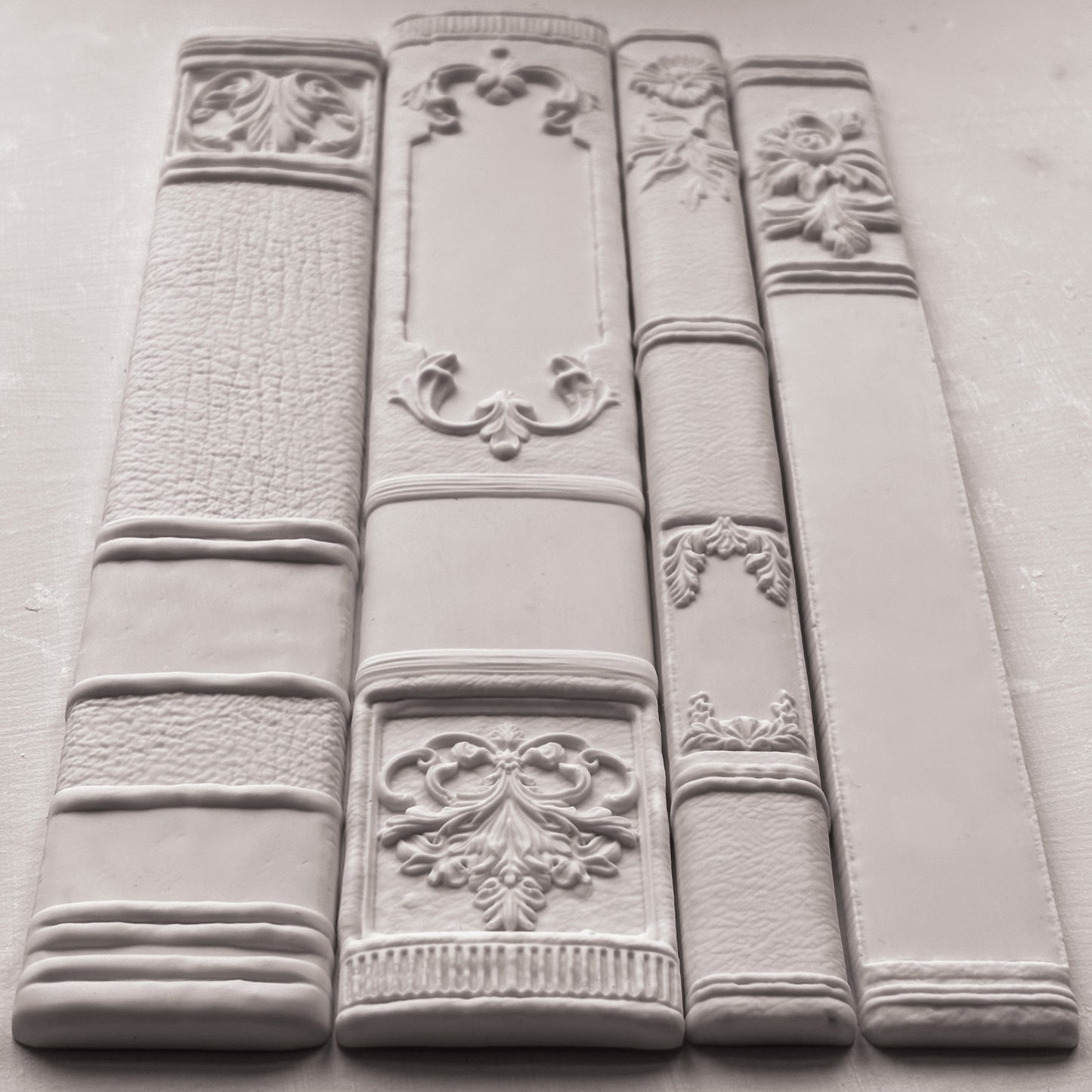 Decorative white bookends with intricate designs on a gray surface