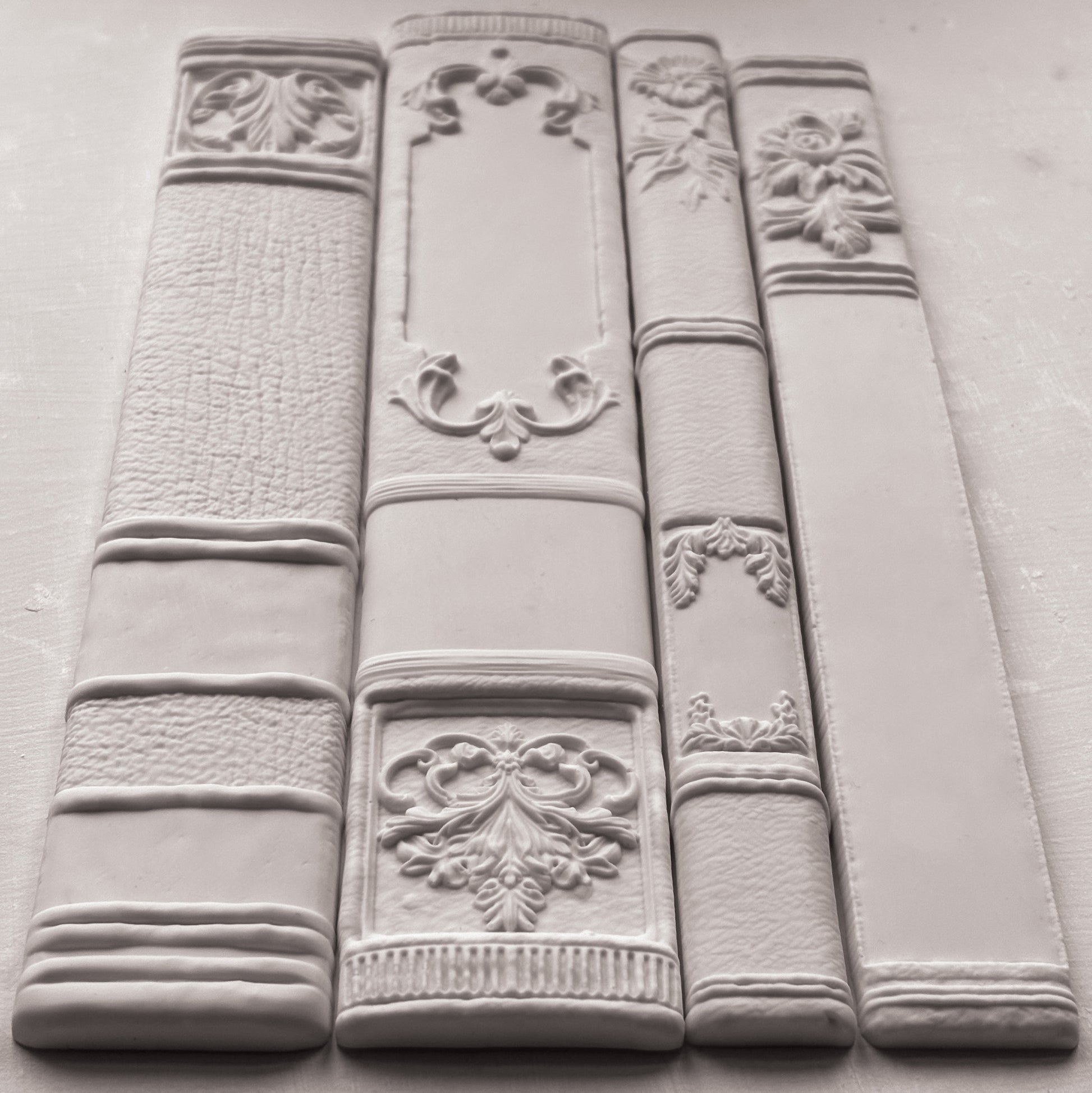 Decorative white bookends with intricate designs on a gray surface