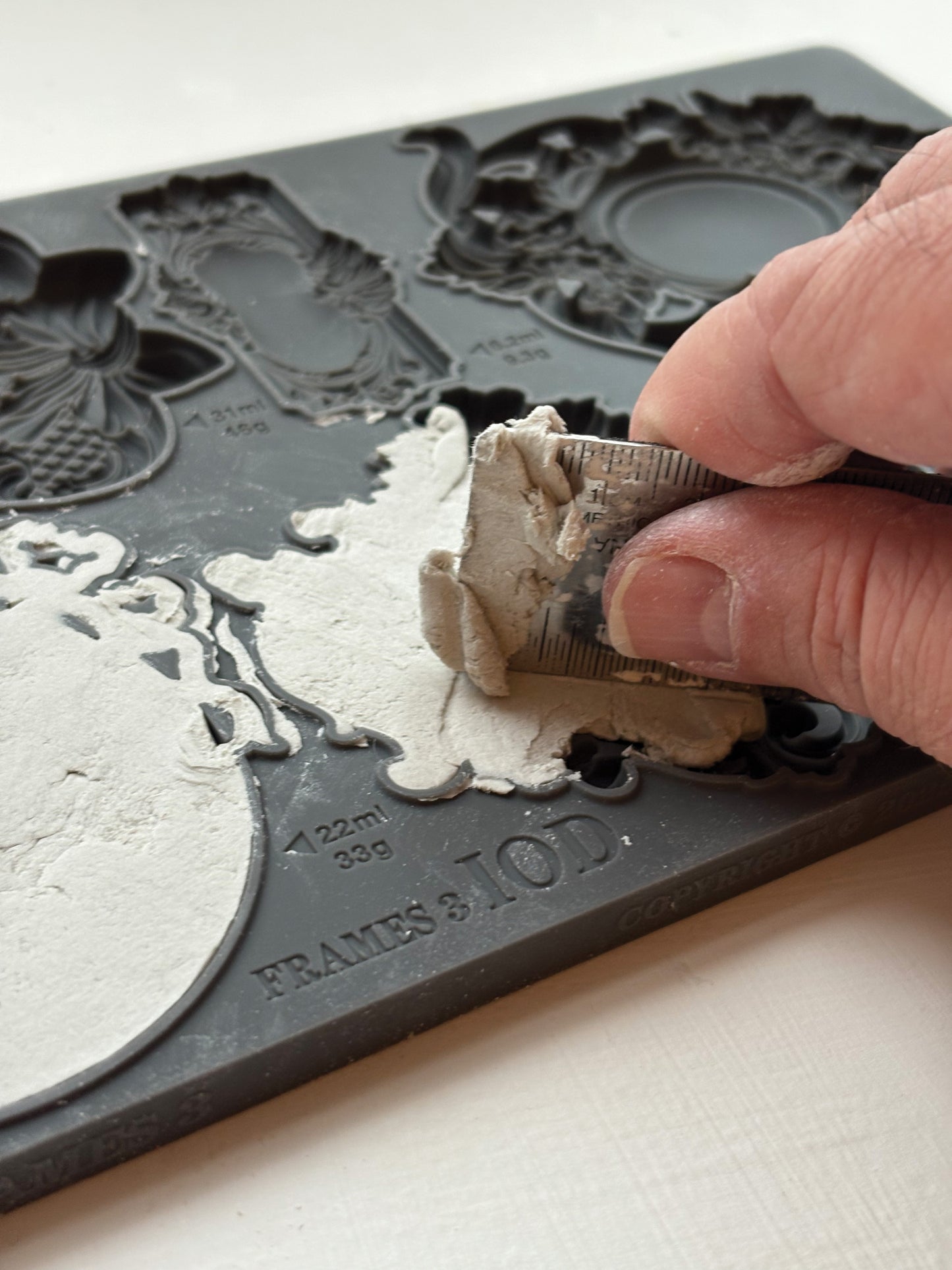 Person using a tool to remove excess material from a decorative mold.