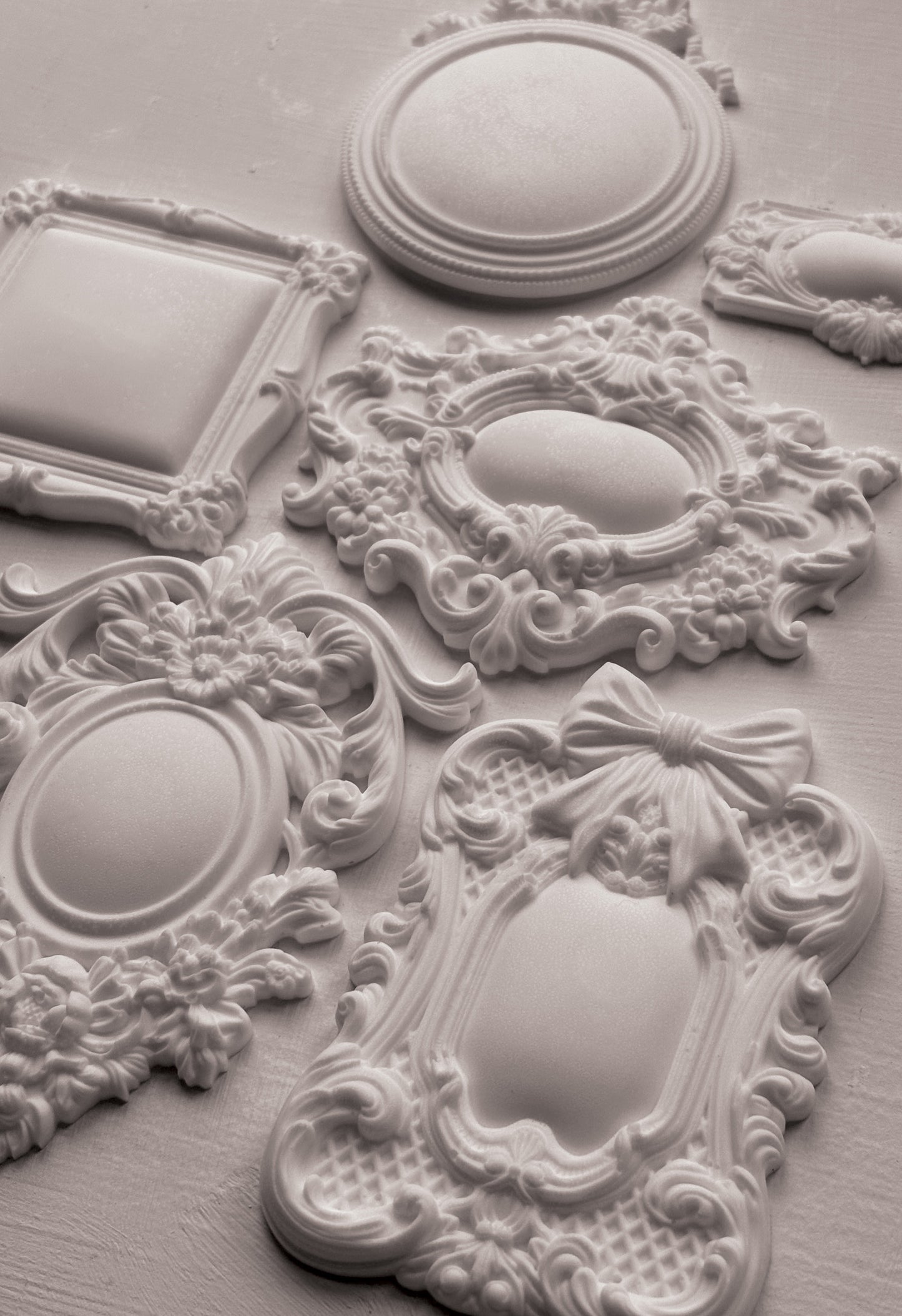 Decorative white ceiling medallions with intricate designs on a light gray background