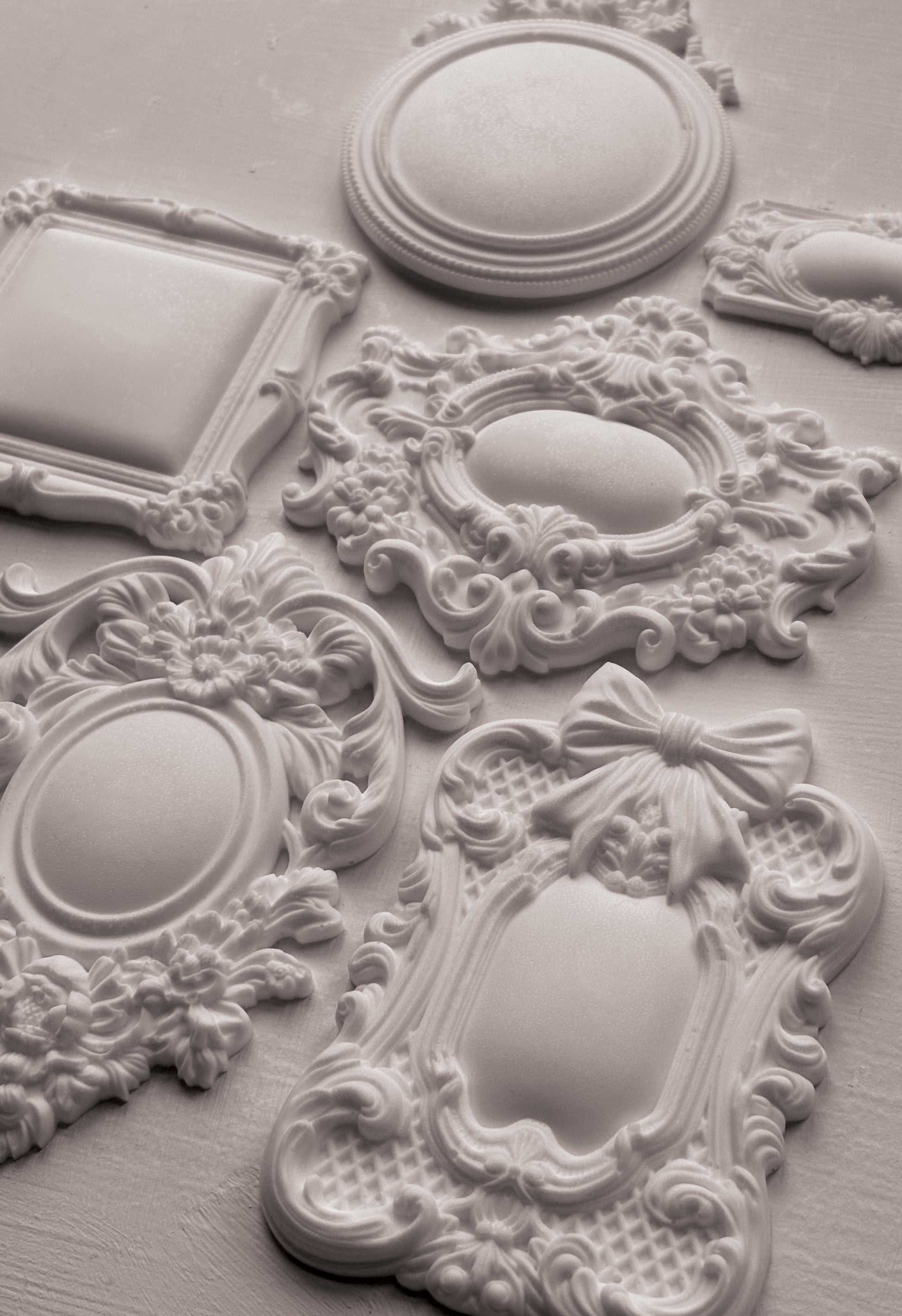 Decorative white ceiling medallions with intricate designs on a light gray background