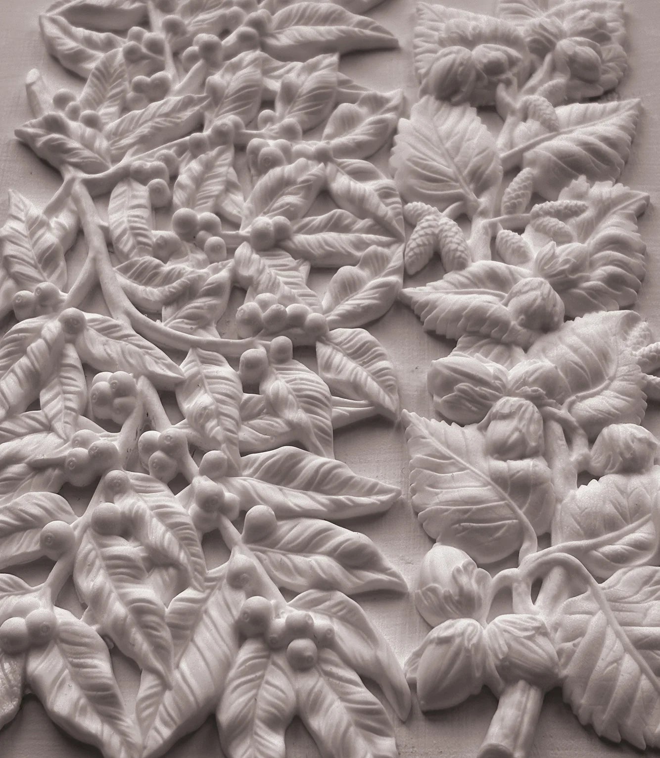 White carved floral and leaf wall art panel with raised botanical details on a light background.