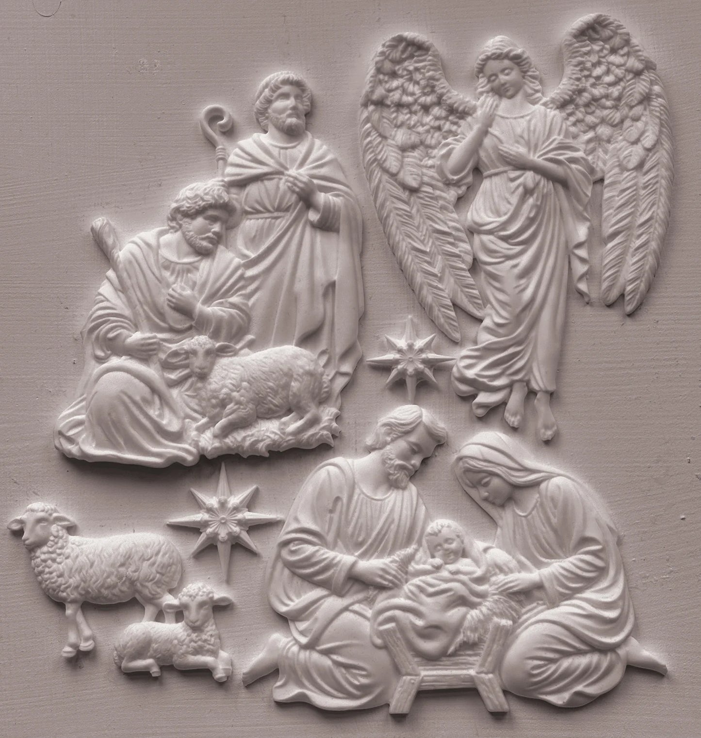 White relief wall plaque featuring a nativity scene with Mary, Joseph, baby Jesus, angels, and sheep, shown against a matching light gray textured background.