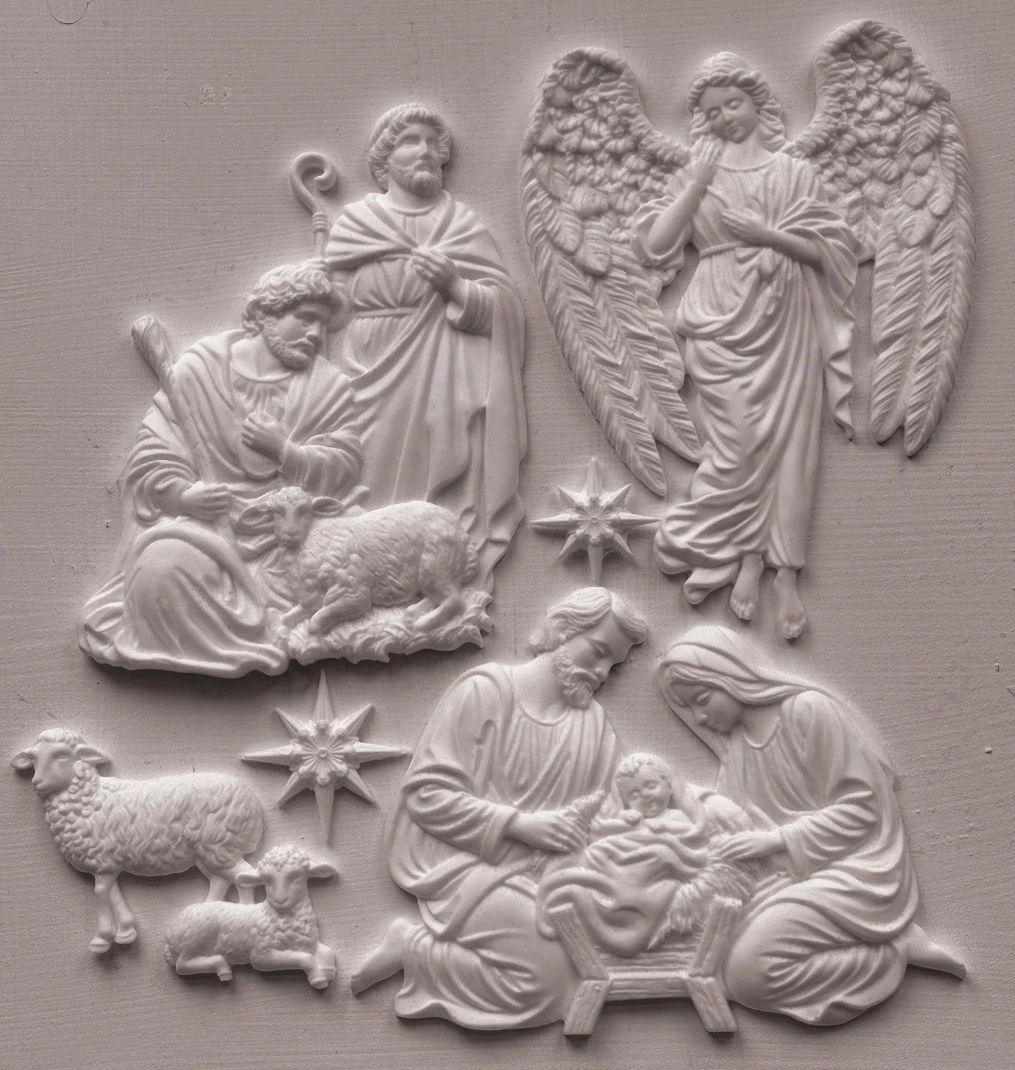 White relief wall plaque featuring a nativity scene with Mary, Joseph, baby Jesus, angels, and sheep, shown against a matching light gray textured background.