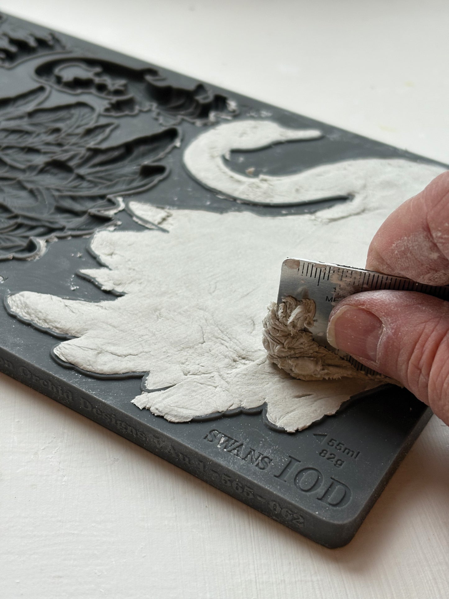 Hand carving a design on a block of material with a tool.