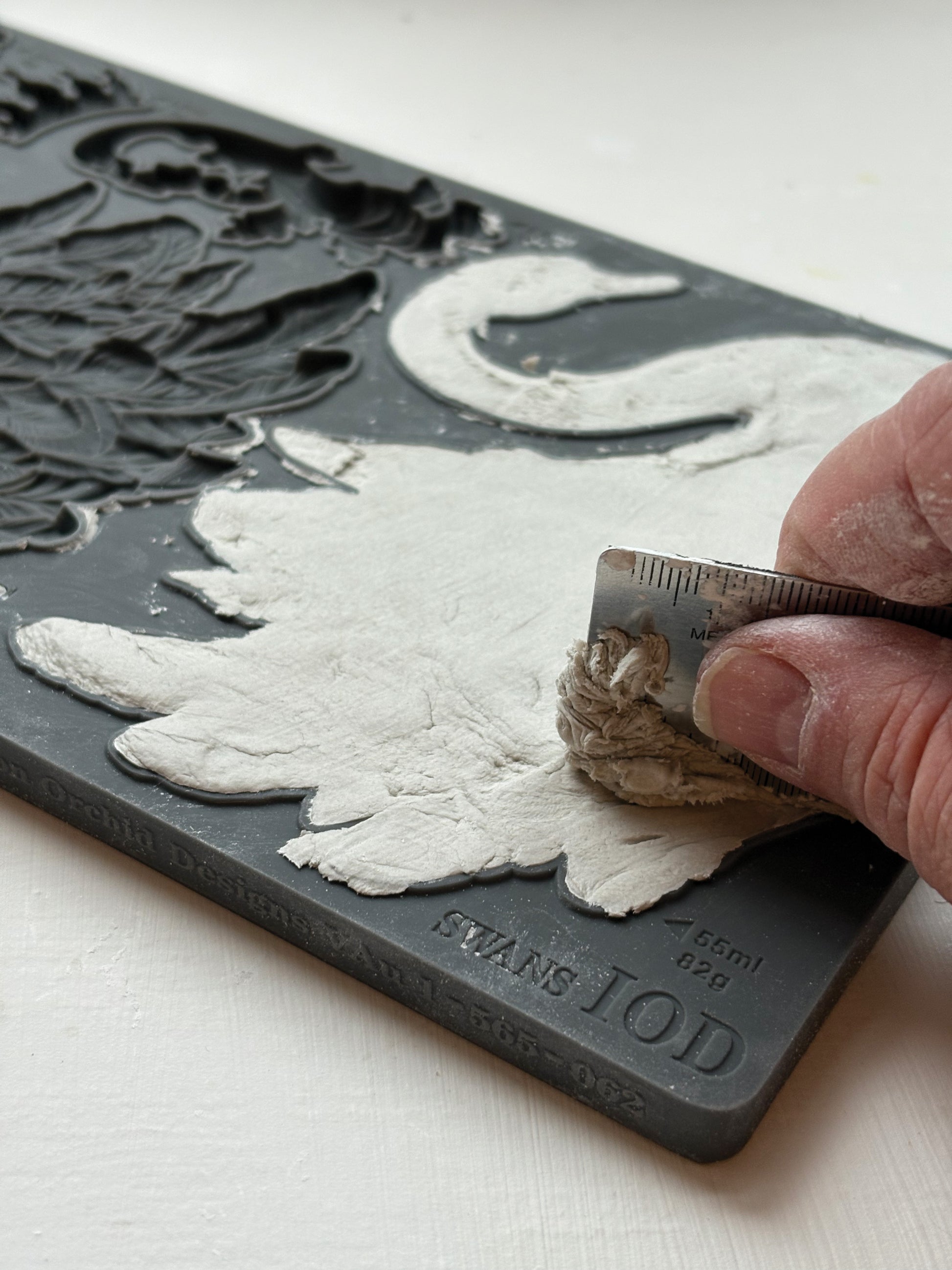 Hand carving a design on a block of material with a tool.