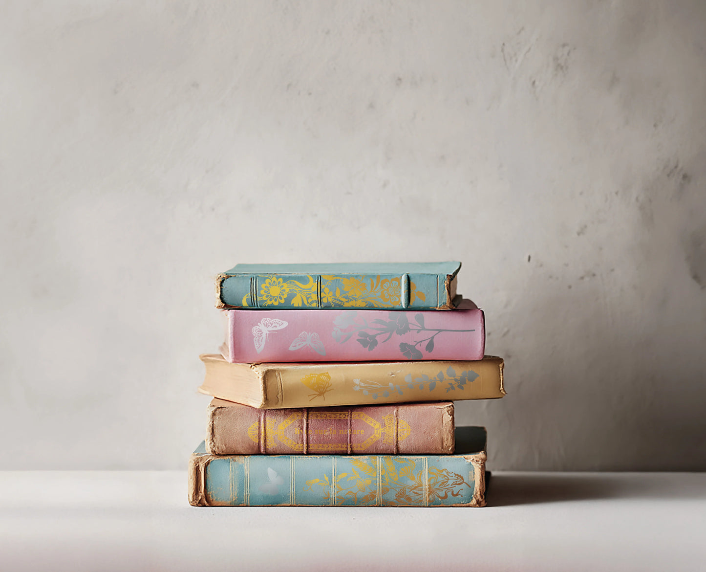 Stack of books with decorative covers on a neutral background