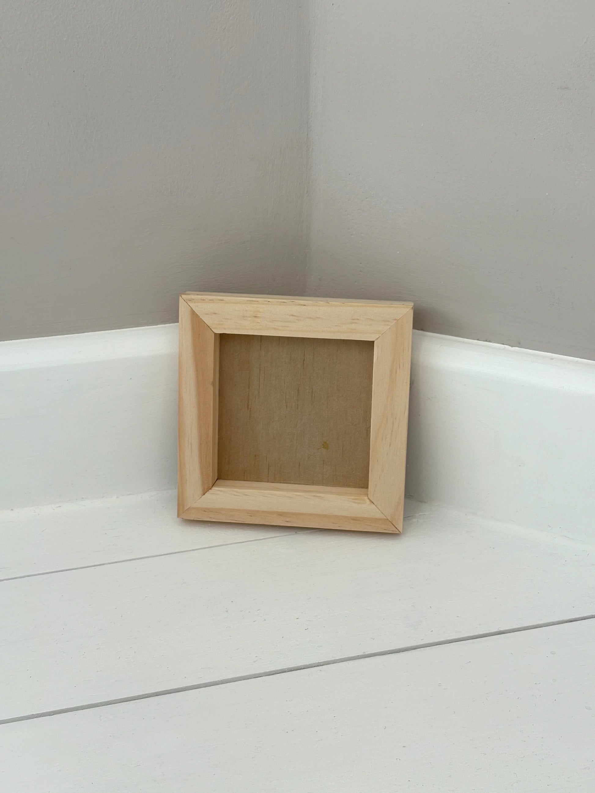 Small wood frame on a white surface with a gray wall background