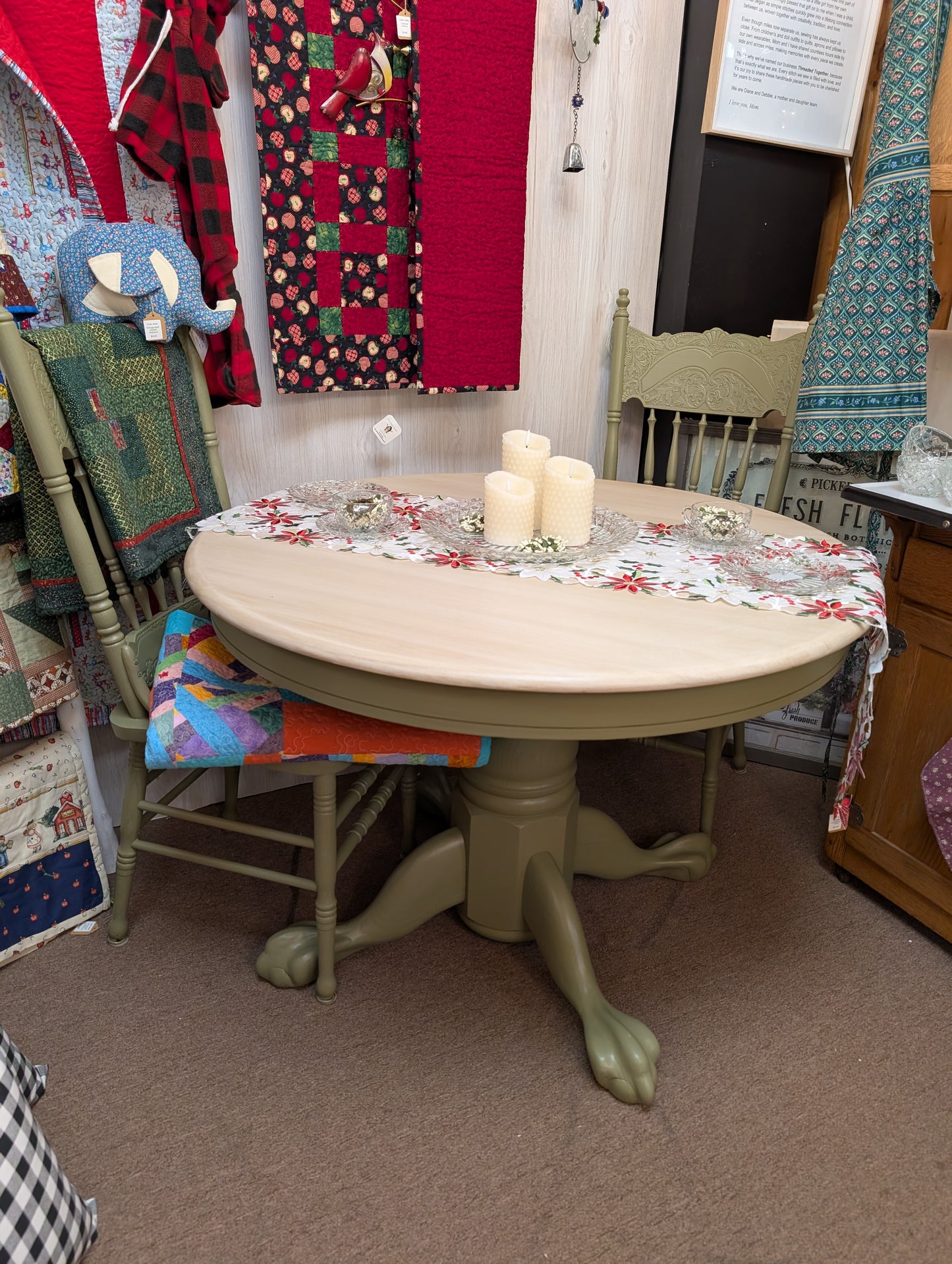 Round table with floral tablecloth and candles in a room with chairs and colorful items.