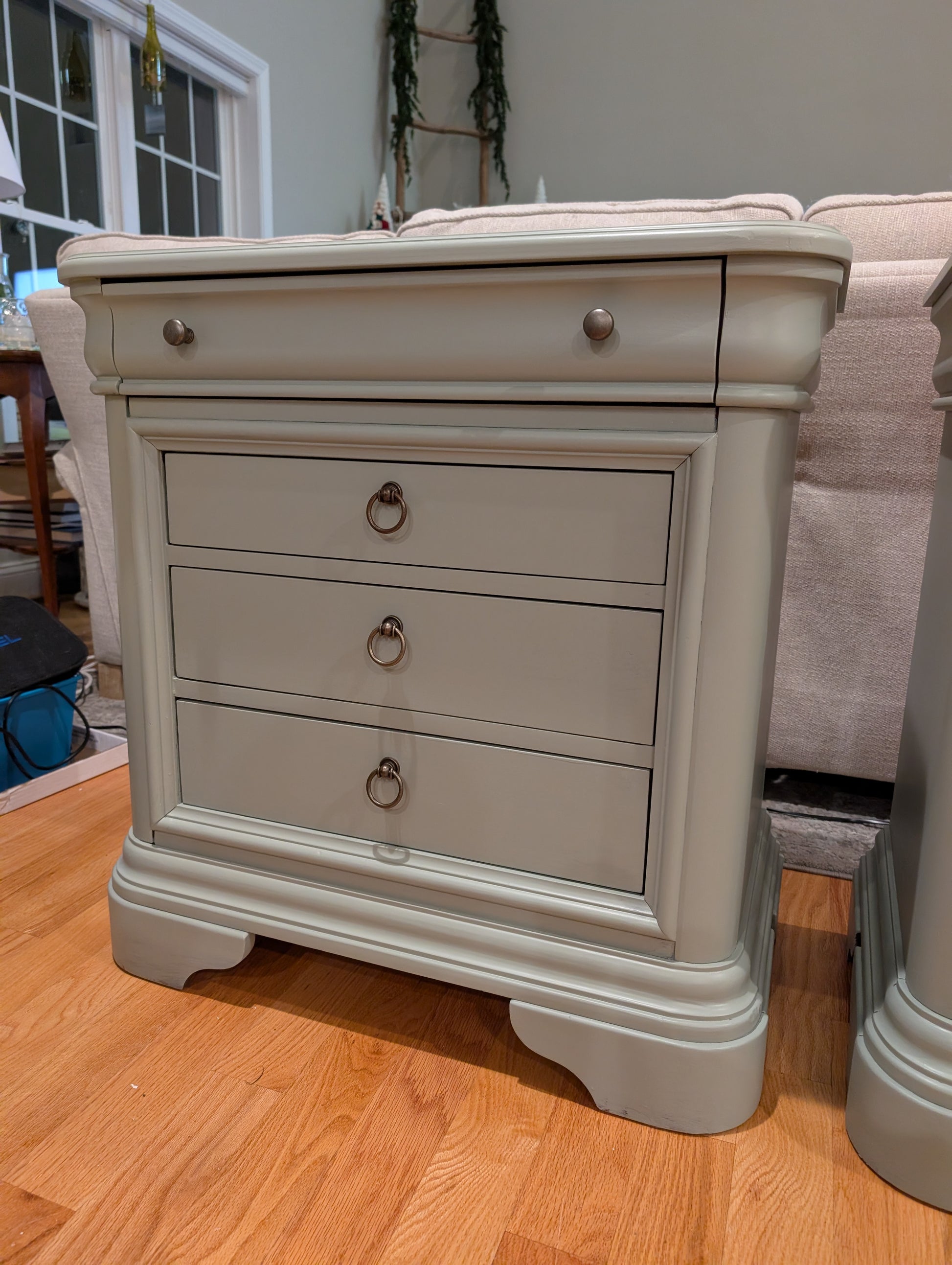 Gray nightstand with three drawers on a wooden floor.
