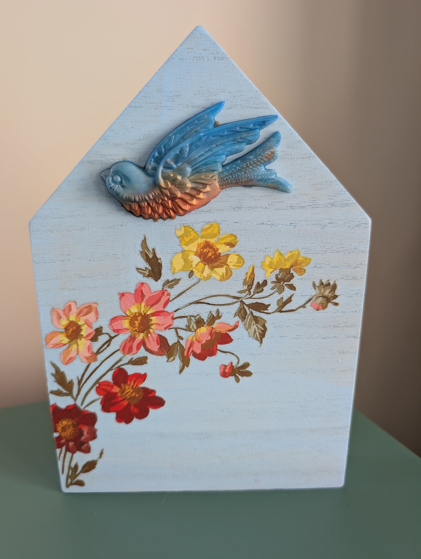 Decorative wooden house with painted flowers and a bird on a plain background