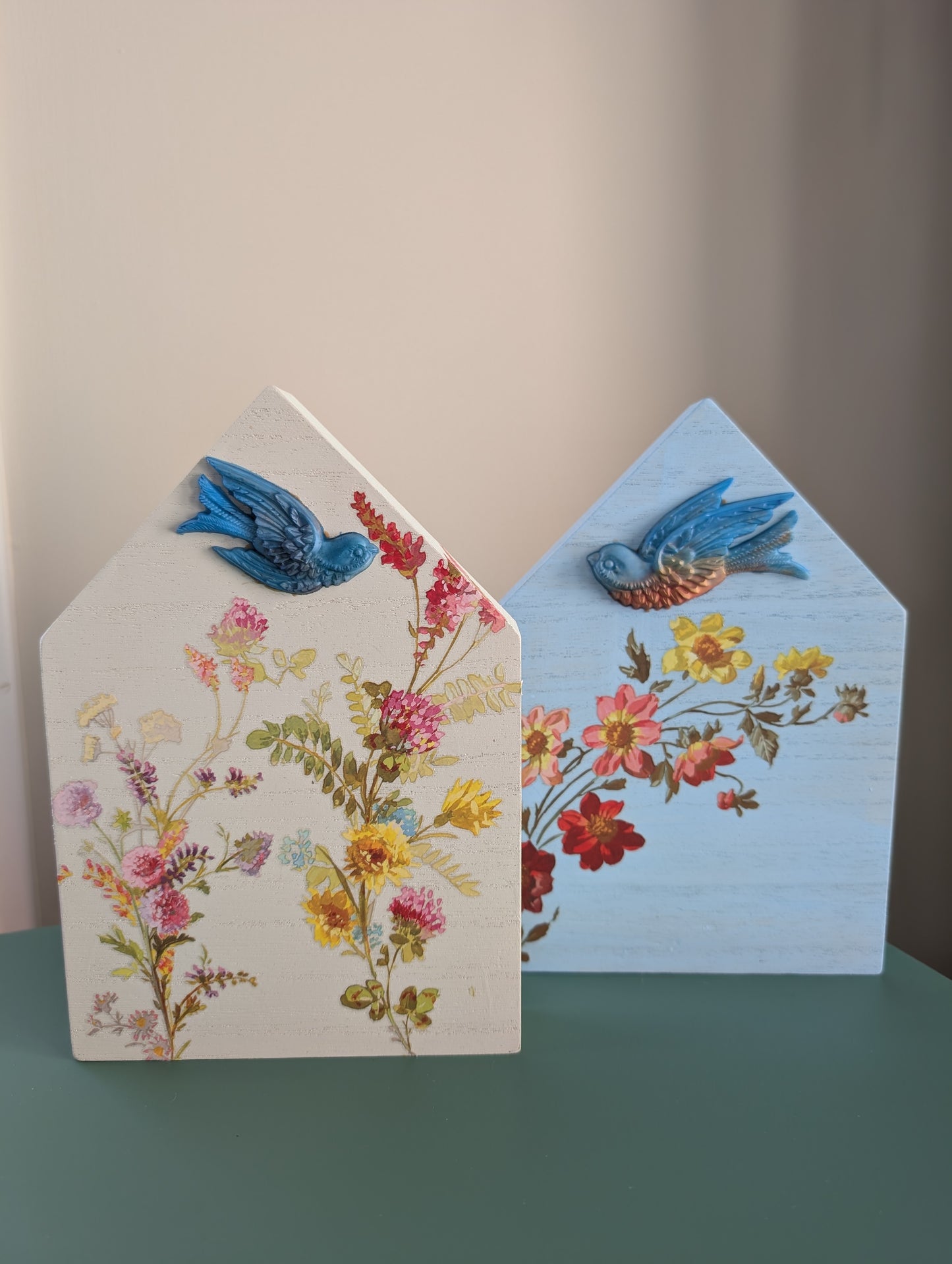 Two decorative house-shaped cards with floral designs and blue birds on a plain background.