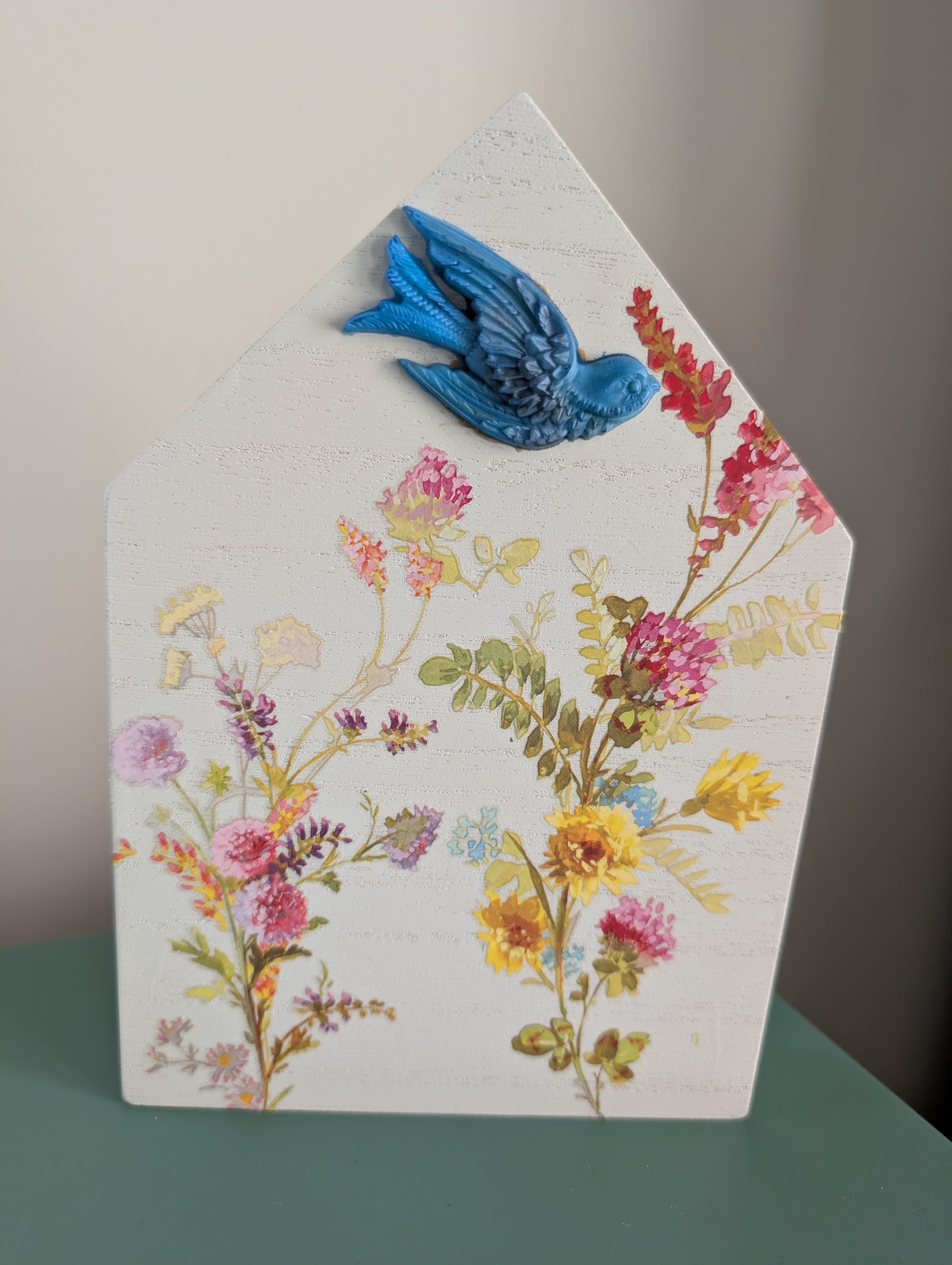 Decorative wall art with flowers and a blue bird on a white background