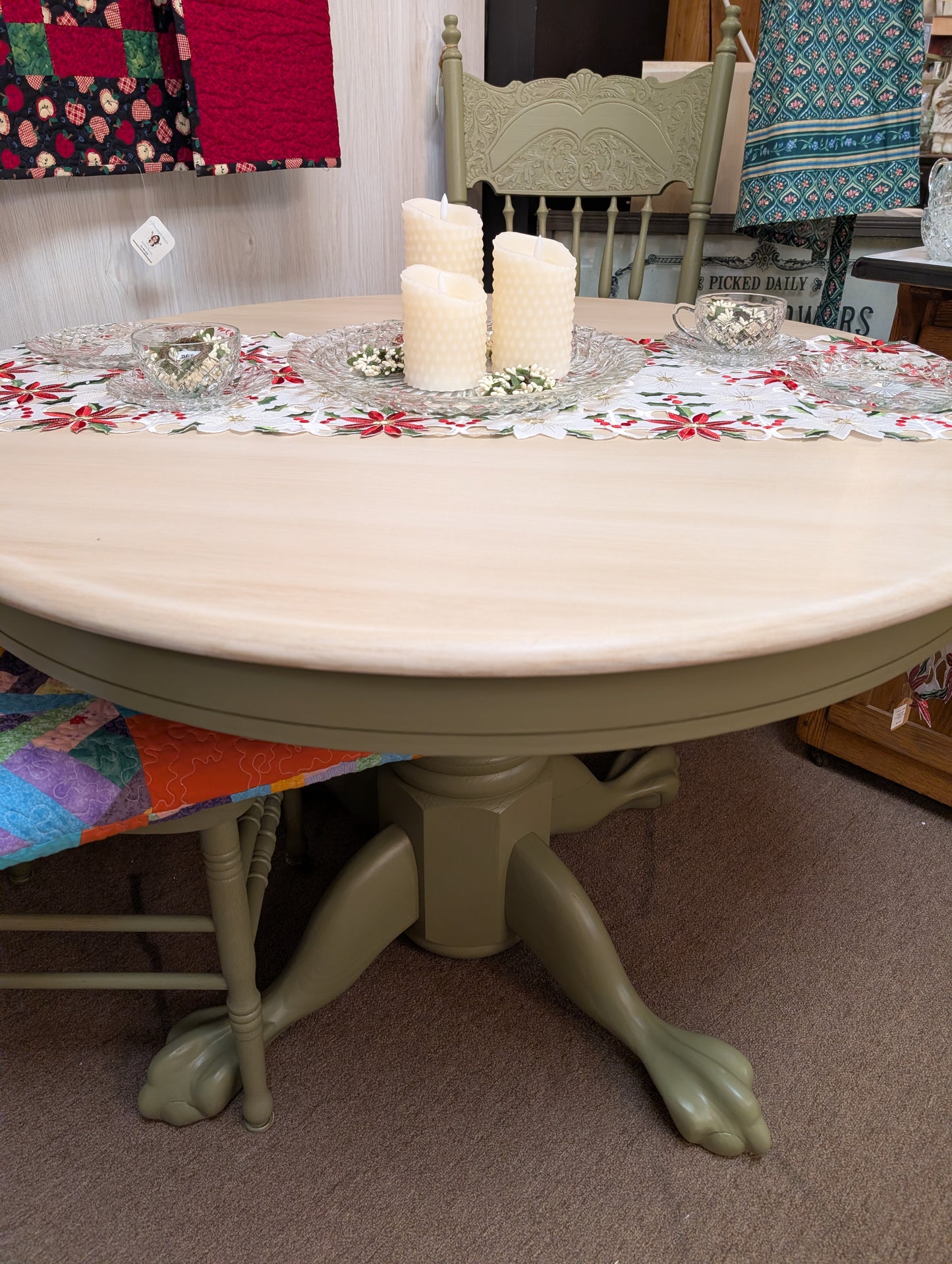 Round table with candles on a floral tablecloth in a room with chairs and colorful fabric.