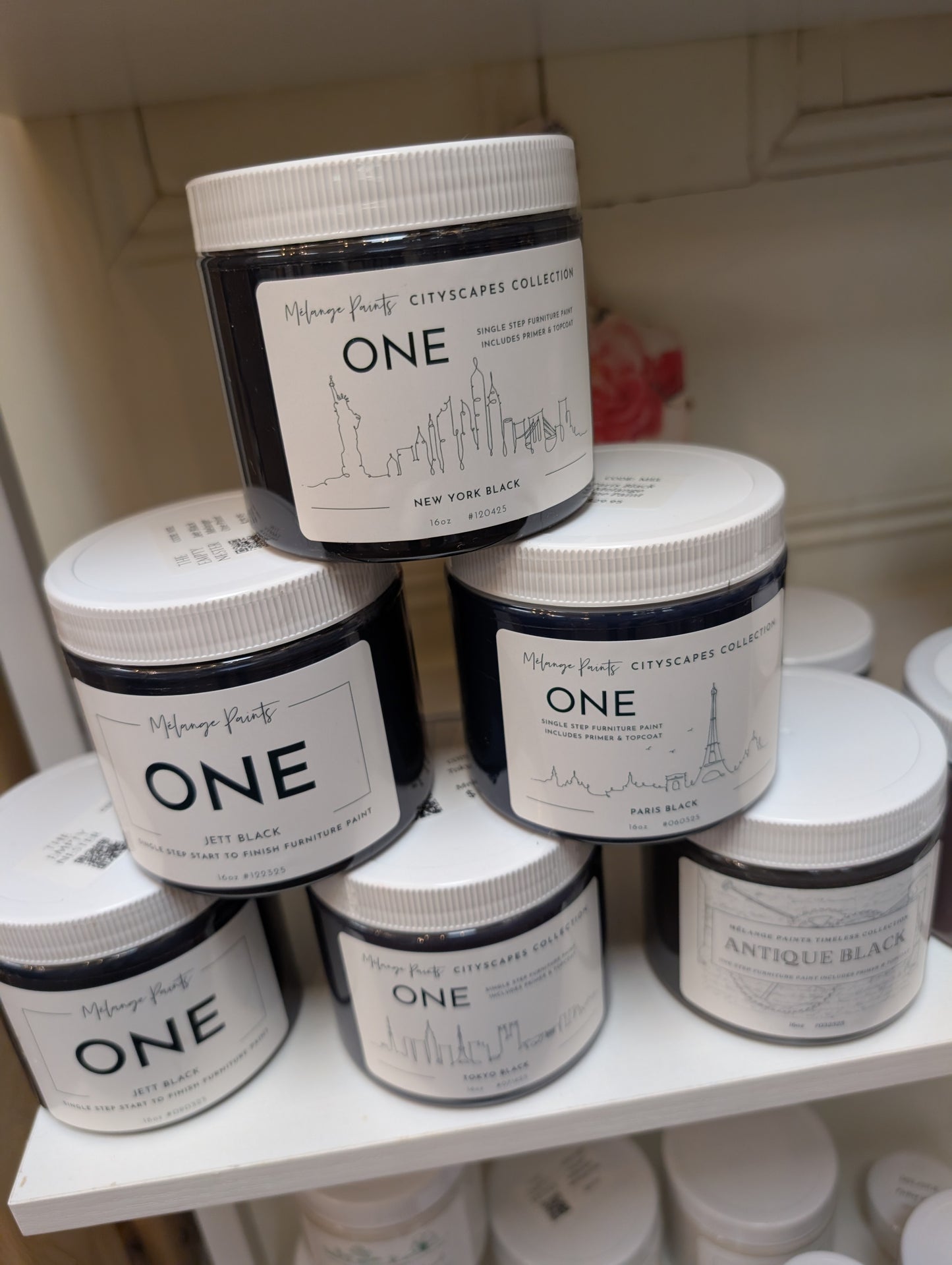 Multiple jars of 'ONE' paint on a shelf with visible branding.